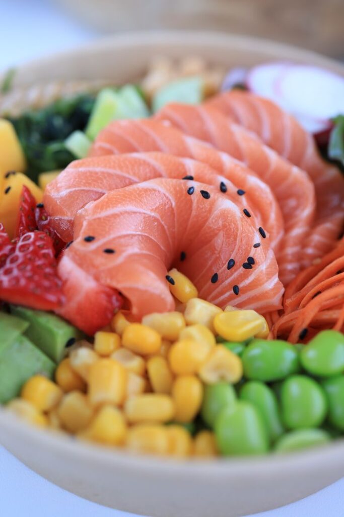 Delicious salmon poke bowl with fresh vegetables and fruits for a healthy meal.